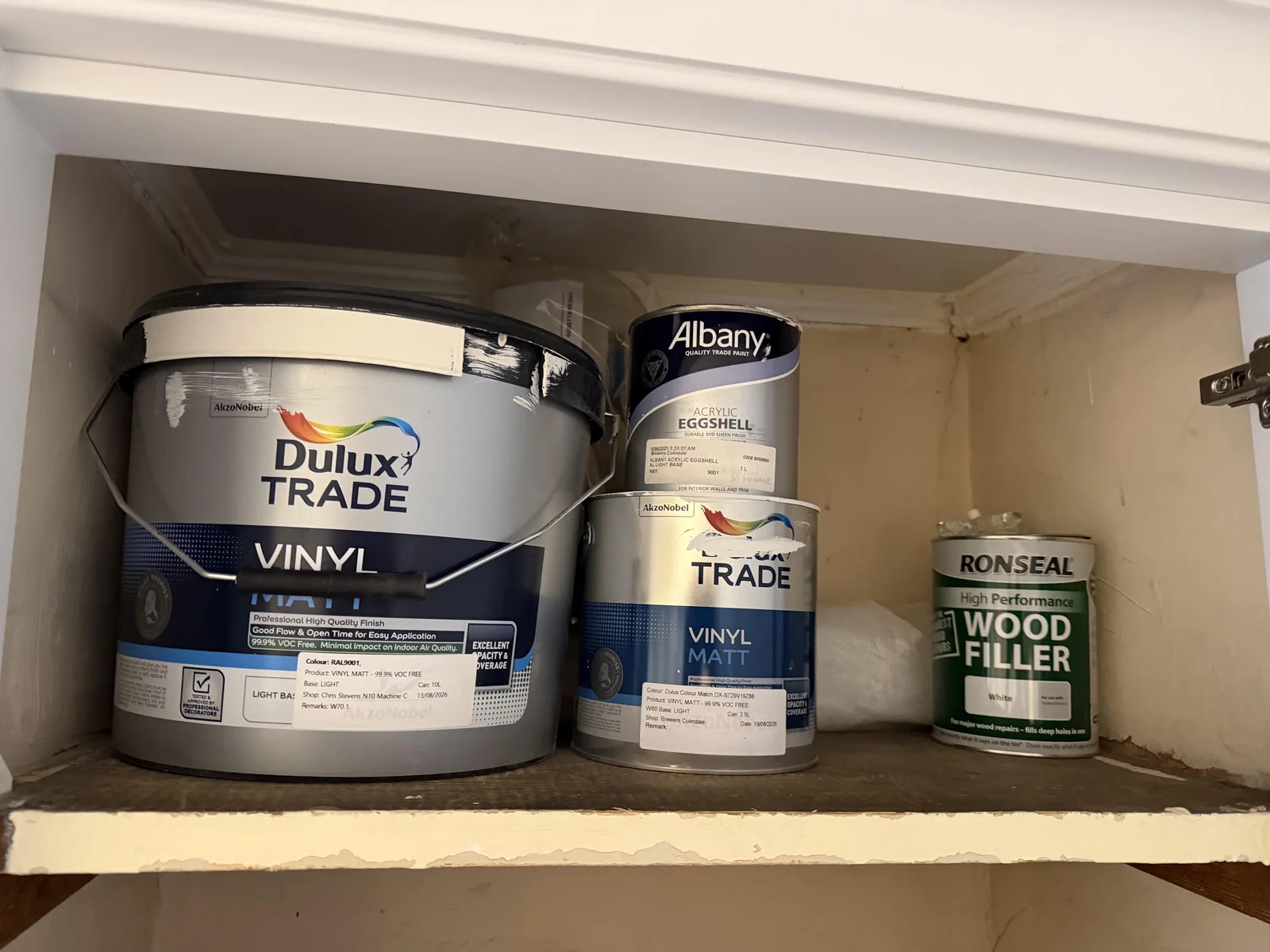 Paint tins and white wood filler in a cupboard