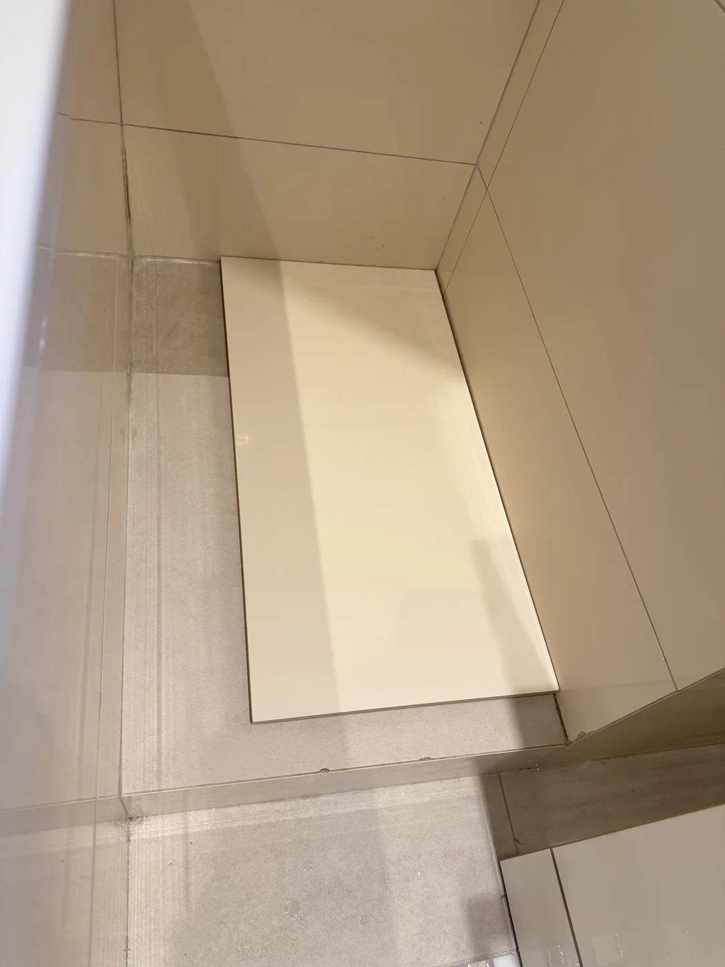 Large loose tile cover over the floor-panel opening beside the bath
